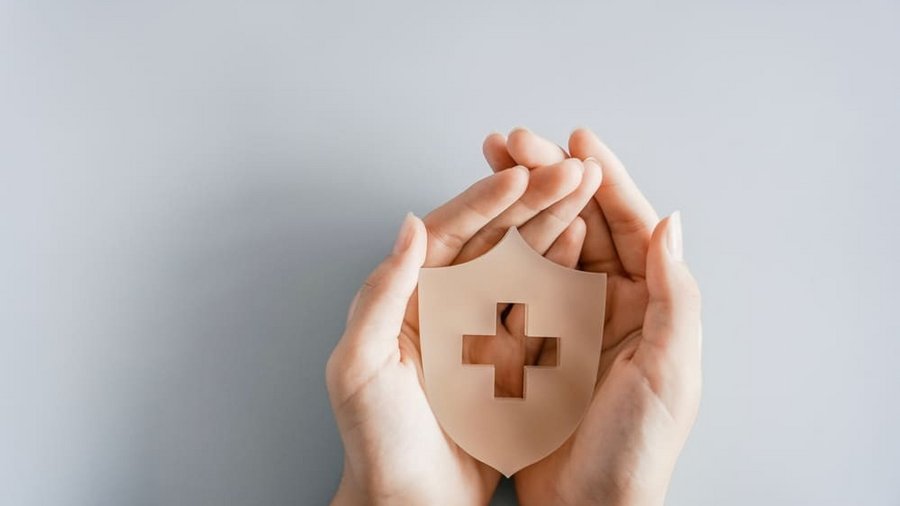 Mâini care țin un scut cu simbolul crucii, asigurare de sănătate, prim ajutor, asistență medicală și concept de bunăstare. Mâini care țin un scut cu simbolul crucii, asigurare de sănătate, prim ajutor, asistență medicală și concept de bunăstare.